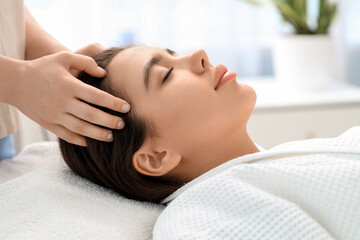 Beautiful young woman having facial massage in salon, closeup