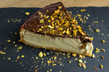 A slice of homemade pistachio cheesecake drizzled with dark chocolate