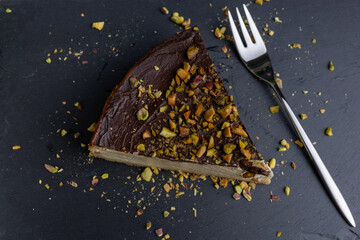 A slice of homemade pistachio cheesecake drizzled with dark chocolate