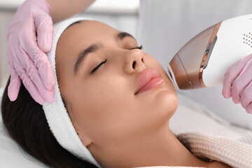 Beautician epilating woman's face in salon, closeup