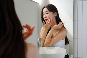 鏡の前でスキンケアをする若いアジア人女性