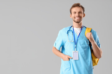 Male medical intern with backpack on light background