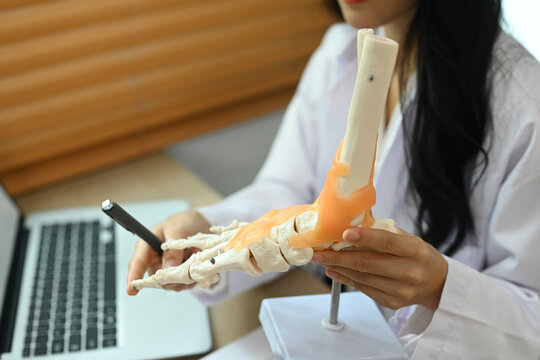 Professional orthopedic doctor explaining to patient about treatment, pointing at model of ankle and foot bones - Powered by Adobe