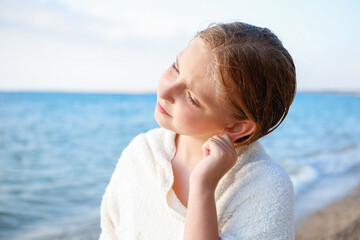The child got water in his ear while swimming in the sea. The girl cleans her ear from water.