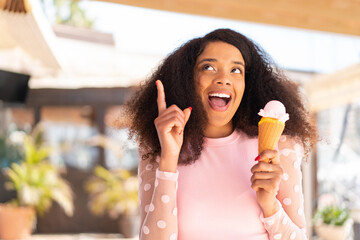 Young African American woman with a cornet ice cream at outdoors pointing up a great idea