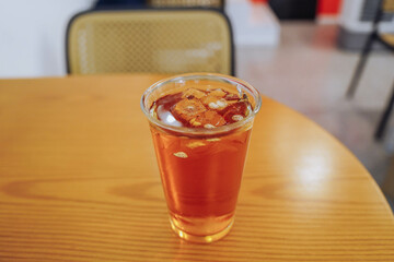 A glass of organic sparkling apple cider with ice on wooden table in restaurant.