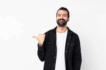 Young man with beard over isolated white background pointing to the side to present a product