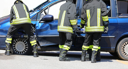 Fototapeta premium team of firefighters using hydraulic shears and jaws of life to pry open the door of a crashed car after an accident
