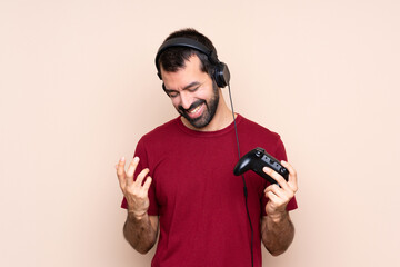 Man playing with a video game controller over isolated wall smiling