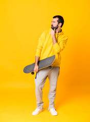 Full-length shot of man over isolated yellow background with a skate and looking lateral