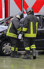 Firefighters using powerful jaws of life and hydraulic ram to pry open door of crashed car on...