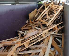 wooden pieces planks and broken pallets in the wood recycling container at the landfill for proper waste disposal