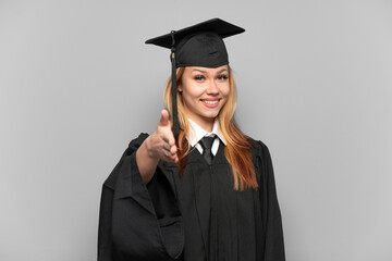 Young university graduate girl over isolated background shaking hands for closing a good deal