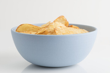 Organic potato chips in blue bowl isolated on white