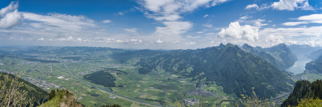 Large panorama of the Linth plain from the Hirzli mountain in summer with blue sky and clouds