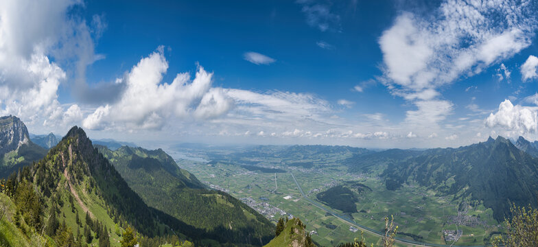 Large panorama of the Linth plain from the Hirzli mountain in summer with blue sky and clouds