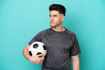 Young caucasian man isolated on blue background with soccer ball