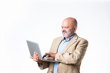 portrait of senior old Indian asian businessman using laptop against white background