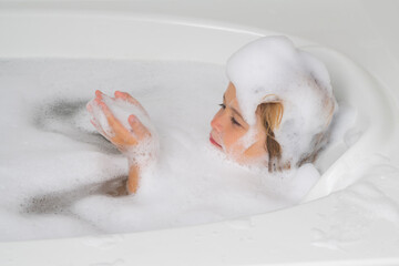 Children bathing. Cute child washing and bathing in a bath with foam. Funny kid face bathed in the bath.