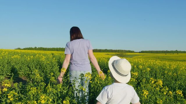 Happy Family Is Walking In Fresh Air. Portrait Of Mother With Son Having Fun In Yellow Field. Joy Family Lifestyle. Family Farmers. Real People.