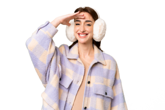 Young caucasian woman wearing winter muffs over isolated chroma key background looking far away with hand to look something