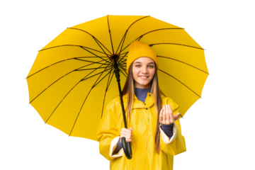 Teenager girl with rainproof coat and umbrella over isolated chroma key background inviting to come with hand. Happy that you came