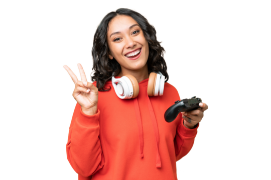 Young Argentinian woman playing with a video game controller over isolated background smiling and showing victory sign