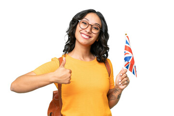 Young Argentinian woman holding an United Kingdom flag over isolated background with thumbs up because something good has happened