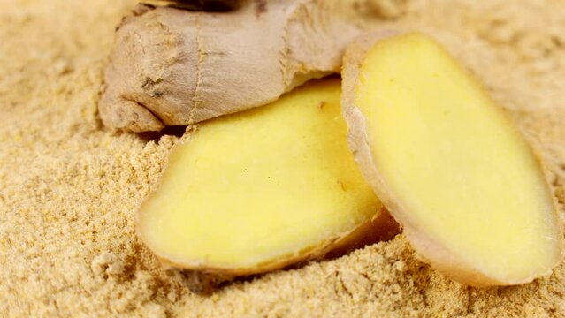 Fresh cut ginger root slices on dried ginger spice powder circle rotation close up