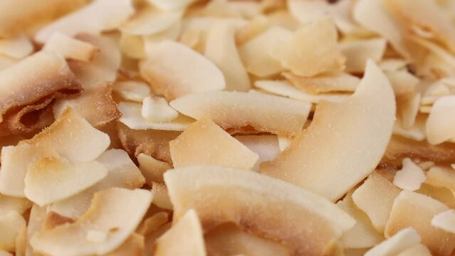 Thin sweet toasted coconut chips circle rotation close up