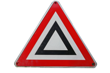 Close-up of a reflective triangular road sign warning drivers to yield, commonly found at intersections and road merges.