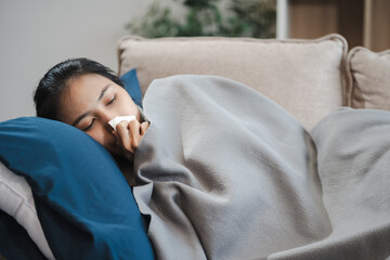 woman sleep on sofa covered with blanket blowing running nose got fever caught cold, Woman feeling...