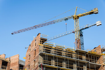 A Pair Of Construction Cranes In Building Site On Blue Sky Background