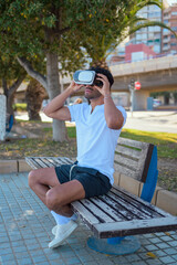 Man wearing virtual reality headset while sitting on a bench in a park