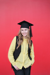 Young beautiful blond female in graduation cap with emotional facial expression on red background. Happy to finish school, college or university High quality photo