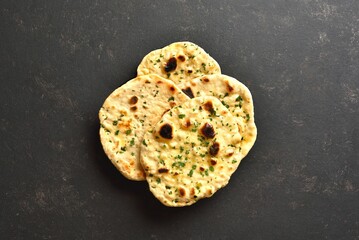 Indian naan bread with greens on dark background