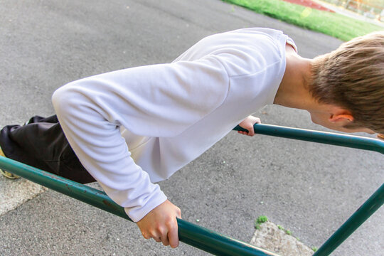 Young Man Performing Dips Exercise on Parallel Bars at Outdoor Gym
