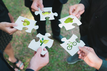 Business people or corporate partnership joining ECO friendly idea puzzle of jigsaw together as...