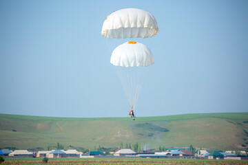 Skydiving. Flying parachutists against the background of the blue sky and mountains. Extreme sport...