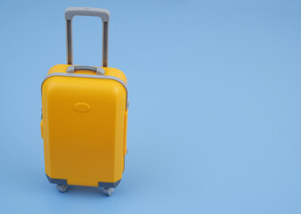 Orange travel suitcase on blue background. Copy space for text. 