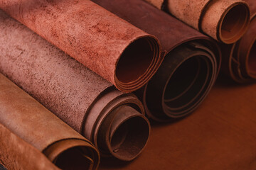 Materials for DIY handmade craft. Different rolls of natural color leather on rack in workshop