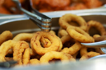 A bowl contains crispy onion rings with a fork on side