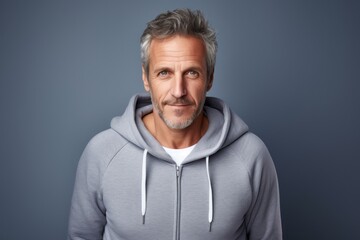 Fototapeta premium Portrait of a merry man in his 50s wearing a zip-up fleece hoodie in light wood minimalistic setup