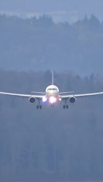 Airplane landing at airport head on generic unmarked white full landing and approach passenger jet