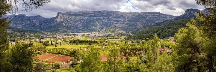 Panoramic view of the verdant S&oacute;ller valley seen from GR-221 hiking trail amidst Serra de Tramuntana mountain range in Mallorca, perfect for nature tourism, hiking adventures and springtime travel.