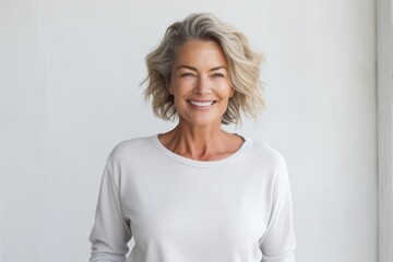 Fototapeta premium Portrait of a smiling woman in her 50s showing off a thermal merino wool top while standing against plain white digital canvas