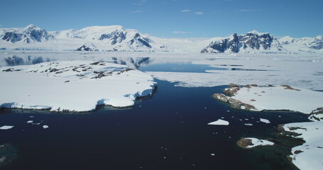 Stunning Arctic winter landscape, snow-covered mountains, polar ocean, frozen water, blue sunny...