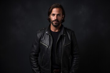 Obraz premium Portrait of a merry man in his 30s sporting a classic leather jacket isolated in plain cyclorama studio wall