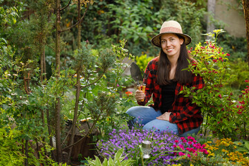 smiling young woman gardener holding shovel and rake in the garden