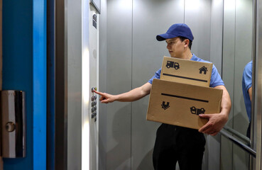 Package delivery man inside an elevator touching a button, dressed with uniform